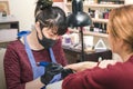 Manicurist in black latex gloves makes a manicure to the client, using a manual electric milling machine in the beauty salon