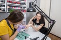 A manicurist covers a client`s nails with varnish in a nail salon