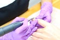 a manicurist gives a manicure to a young woman in purple gloves.