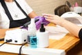 a manicurist gives a manicure to a young woman in purple gloves.