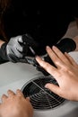 Manicurist in gloves is applying transparent nail base gel on female finger nails. Royalty Free Stock Photo