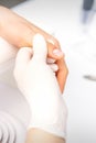 The manicurist holds the female thumb during a manicure procedure in the nail salon.