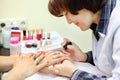 Manicurist makes manicure for woman by nail polish