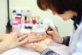 Manicurist manicures woman by pink nail polish