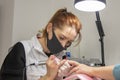 A manicurist in a medical mask files and cleans the client`s nails, close-up.