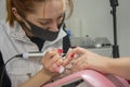 A manicurist in a medical mask files and cleans the client`s nails, close-up.