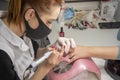 A manicurist in a medical mask files and cleans the client`s nails, close-up.