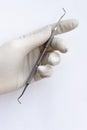 A female hand in a white glove holds a metal tool for manicure and pedicure on a white background. Vertical frame