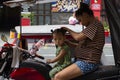 Manila, the Philippines - 14 April 2018: Mother making hair to little daughter on tricycle. Poor filippino family