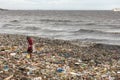 A man collecting plastic waste in a pile of garbage in the sea