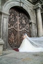 Bride in wedding dress and veil waiting outside old church