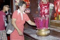 Matured Woman light candle and joss stick to pray for departed relatives in Chinese temple in Manila