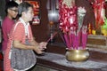 Woman light candle and jots stick to pray for departed relatives in Chinese temple in Manila