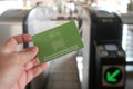 Manila, Philippines: hand holds Light Rail Transit 1 Single Journey Ticket in front of tap machines. Close-up of LRT-1 smart card.