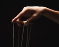 Manipulators hand with marionette string isolated on black Royalty Free Stock Photo