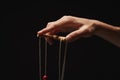 Manipulators hand with marionette string isolated on black Royalty Free Stock Photo