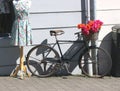 Mannequin with colorful floral dress by bicycle with basket of flowers.