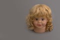 Mannequin head of a little girl looking straight ahead with golden curls on a gray background with coy space. Shop concept, sale, Royalty Free Stock Photo