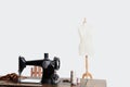 Mannequin and sewing machine with threads over gray background Royalty Free Stock Photo