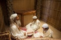 Mannequins depicting scene of old muslim man teaching Koran two young boys