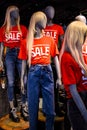 Mannequins In A Window Of A Clothing Store In T-Shirts With Signs Advertising Sale