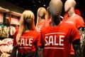 Mannequins In A Window Of A Clothing Store In T-Shirts With Signs Advertising Sale