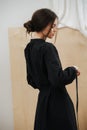 Mannered young beautiful woman tying her dress on a waist. Head in profile.