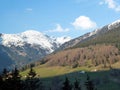 Manors with cottages are located on a mountain slope overgrown with forest. Picturesque natural landscape with blue sky