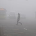 Mans crossing street on crosswalk in mist of early morning. Poor visibility. Foggy weather