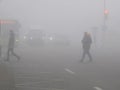 Mans crossing street on crosswalk in mist of early morning. Poor visibility. Foggy weather