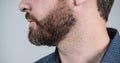 Mans face cropped view with bearded skin and facial hair grey background, skincare