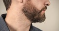 Mans face cropped view with bearded skin and facial hair grey background, skincare