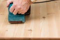 Mans hand on belt sander on pine wood