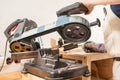 Mans hand cuts rolled metal products on band saw