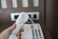 Mans hand holding handset of white vintage telephone with grey battoms on a brown table in hotel. Royalty Free Stock Photo