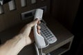 Mans hand holding handset of white vintage telephone with grey battoms on a brown table in hotel. Royalty Free Stock Photo