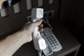 Mans hand holding handset of white vintage telephone with grey battoms on a brown table in hotel. Royalty Free Stock Photo