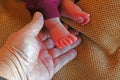 Mans hand holding new born baby's small feet.