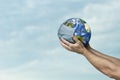 Mans hand holding planet Earth wearing a mask Royalty Free Stock Photo