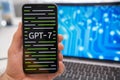 A mans hand holding a smartphone with GPT 7 neural network logo on the screen
