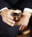 Its a mans world. Mans hand holding a whiskey glass balanced on his knee. Royalty Free Stock Photo