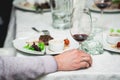 Mans hand holds a glass of wine. fresh grilled bbq roast beef steak and sauce on a white plate with green leaf of salad Royalty Free Stock Photo