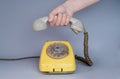 Mans hand laying an old plastic telephone receiver on the levers of a telephone on a gray background. Close up remote Royalty Free Stock Photo