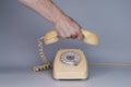 Mans hand laying an old plastic telephone receiver on the levers of a telephone on a gray background. Close up remote Royalty Free Stock Photo