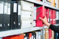 Mans hand picking a blank blind folder with files from the shelf. Archival, stacks of documents at the office or library