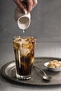 Mans Hand Pours Cream into Glass of Iced Coffee