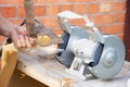 Mans hand sharpens a hoe on electric grindstone in rural shed