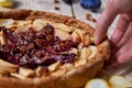 Mans` hand take a piece of apple plums pie. Homemade pie on wooden brown background Royalty Free Stock Photo