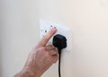 Mans hand turning off plug socket