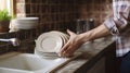 Mans hand wipe with towel a clean plate after washing all the dishes with dishwasher liquid in the vintage kitchen. Generative A